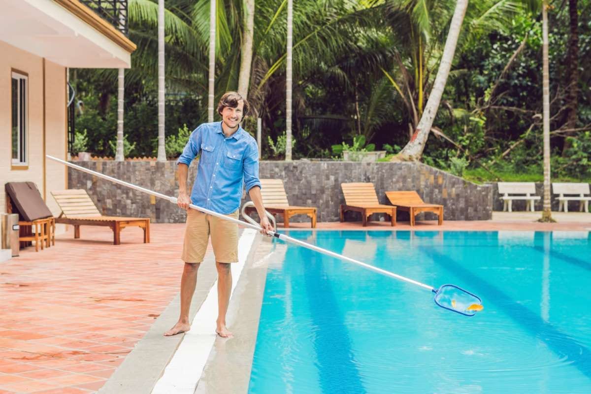 Pool technician skimming a swimming pool with a net
