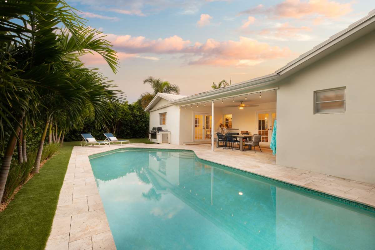 Modern backyard with pool, stone path, artificial grass, trees and patio chairs