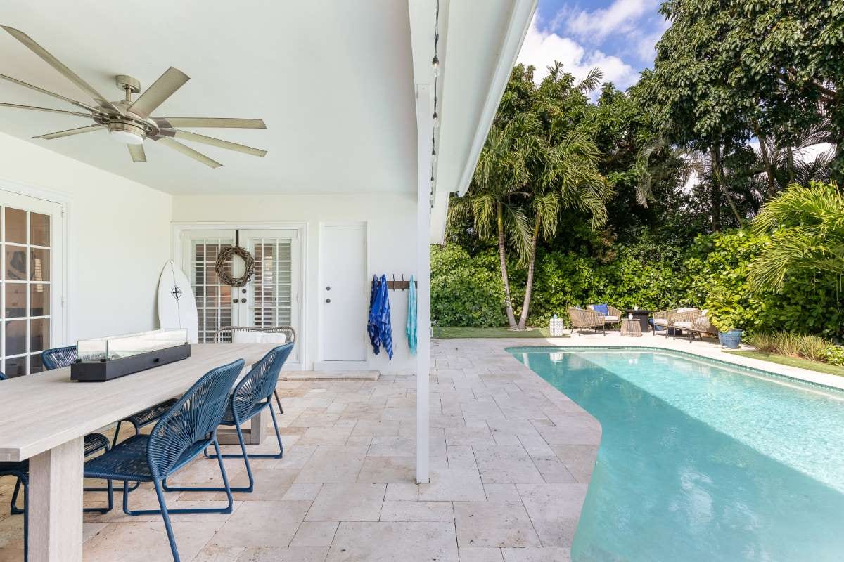 Modern backyard with swimming pool, artificial grass, stone path, trees, and chairs