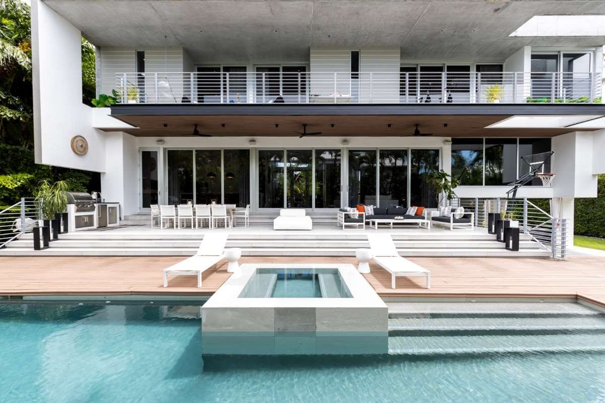 Modern backyard with swimming pool, artificial grass, stone path, trees, and patio chairs