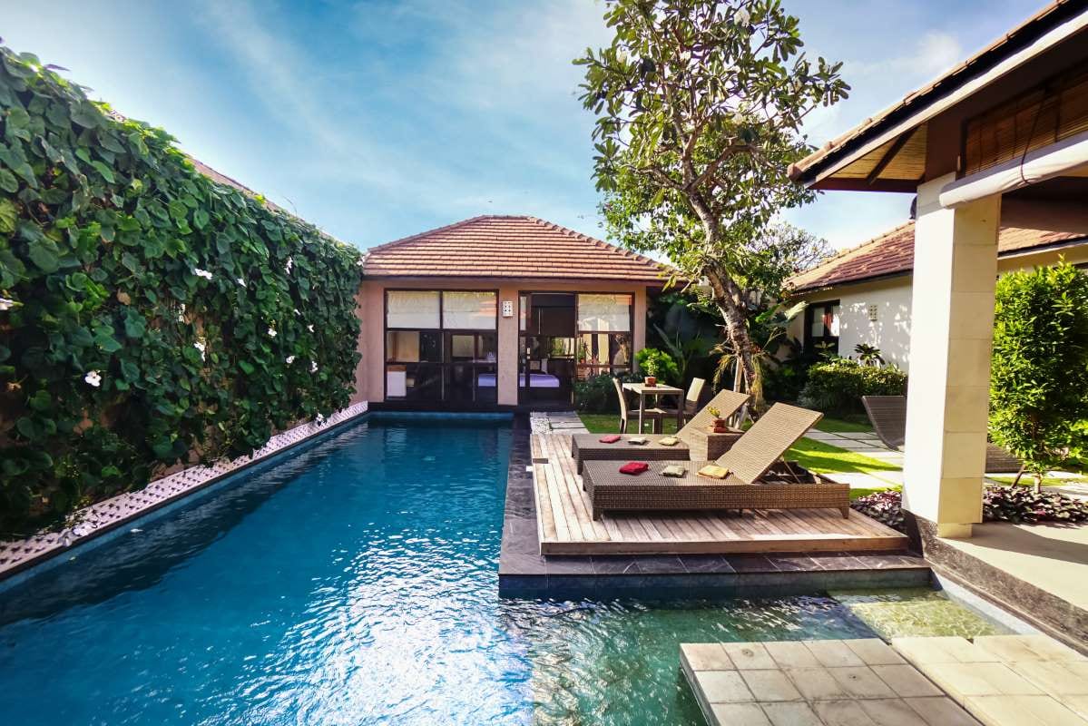 Contemporary home with pool, tropical plants, and blue water in a landscaped garden