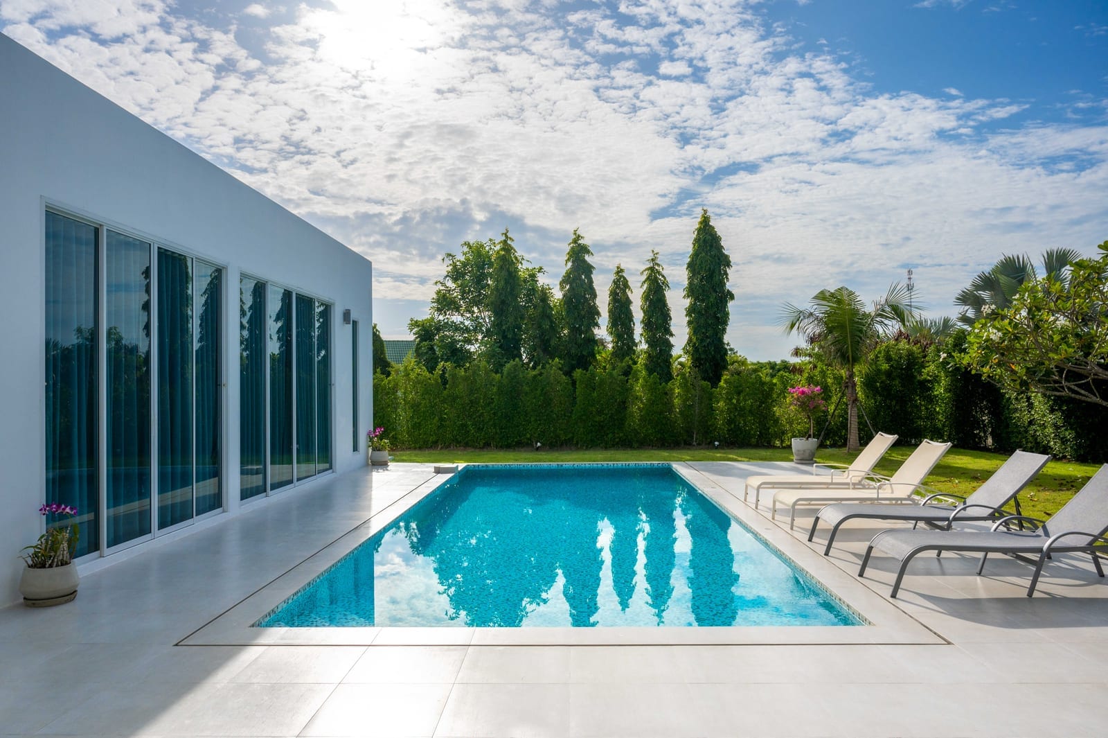 Chairs by a pool house beside a quiet pool, suggesting off-peak relaxation