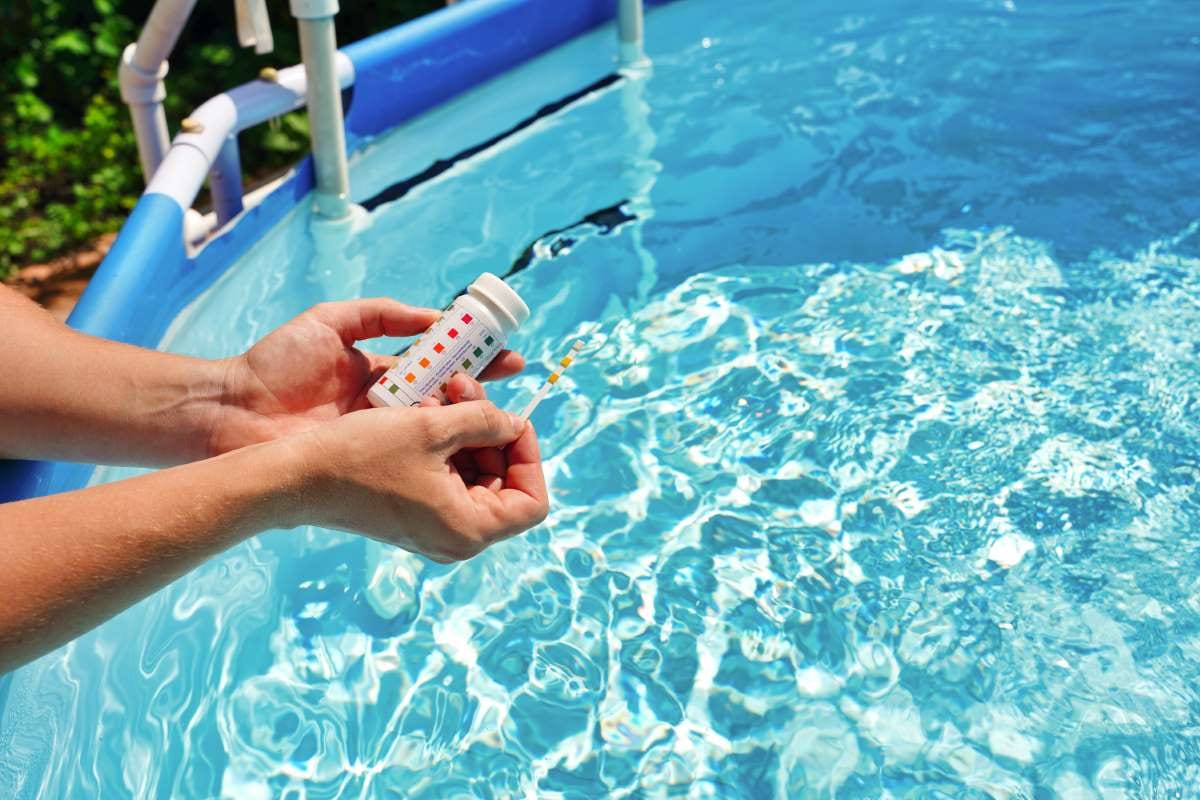 Pool water quality test strip checking pH, chlorine, and algaecide levels