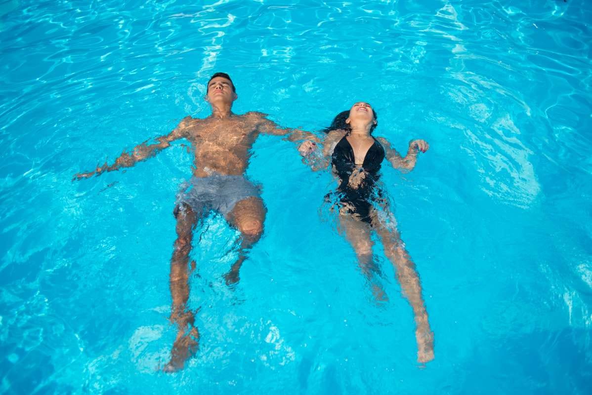 Couple swimming in turquoise pool on vacation