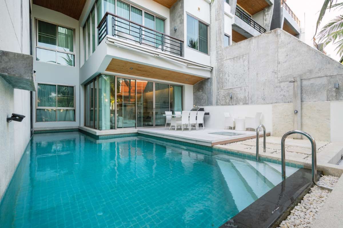 Modern villa exterior with outdoor swimming pool and patio seating