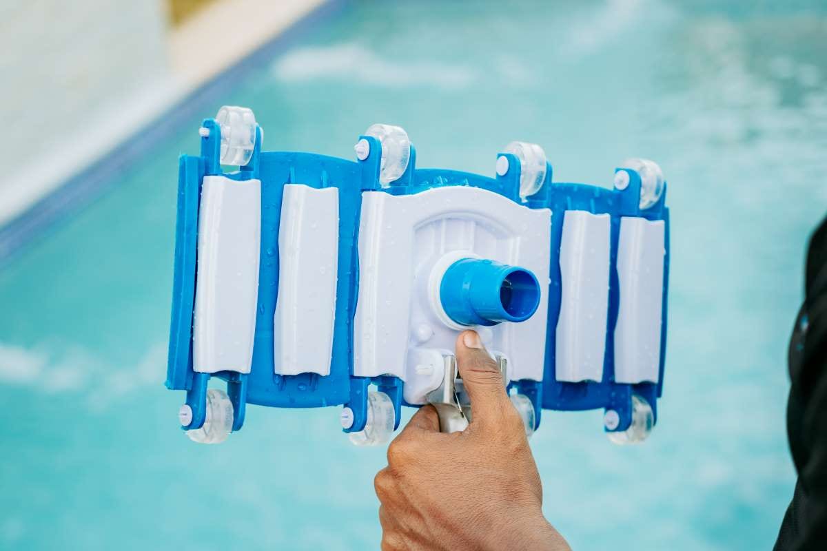 Hand holding a swimming pool sweeper head for pool cleaning and filtration tools concept