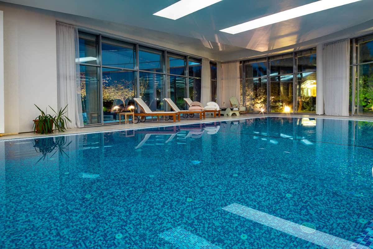 Indoor pool in a private villa overlooking a park through evening windows