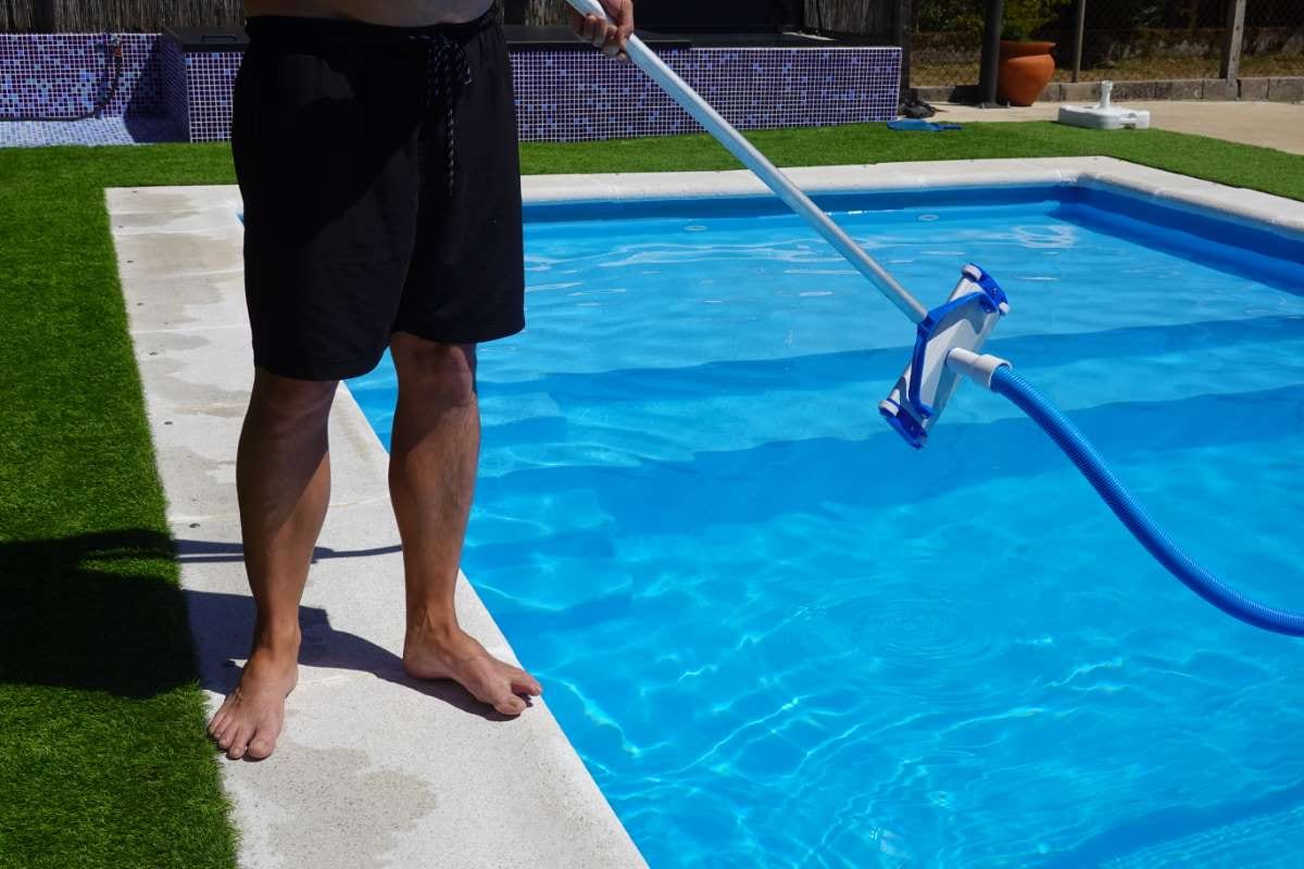 Man cleaning a private pool with a pool vacuum, ready to clean the bottom