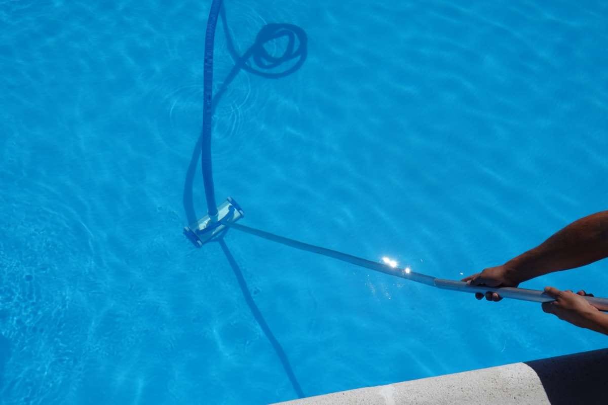 Man holding pool cleaner beside a clean private hotel pool