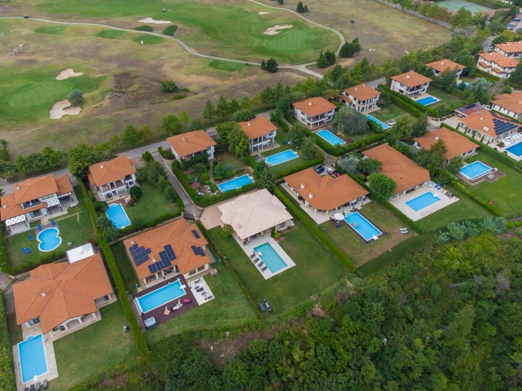Aerial view of a modern cottage village with luxury homes, pools, and golf courses