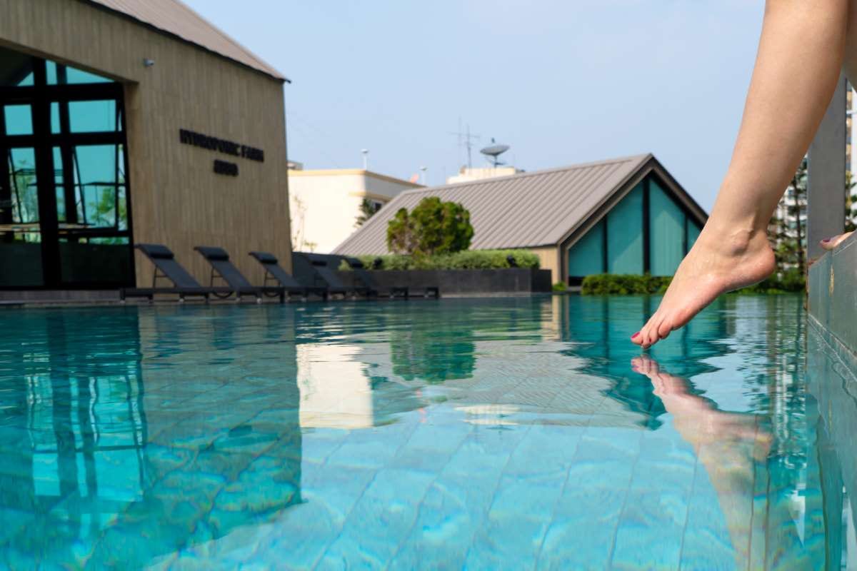Pool technician checking water temperature at a backyard pool