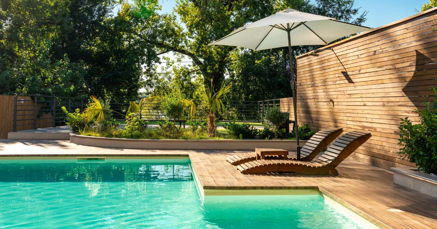 Modern private villa pool with lounge chairs, palm trees, and an umbrella