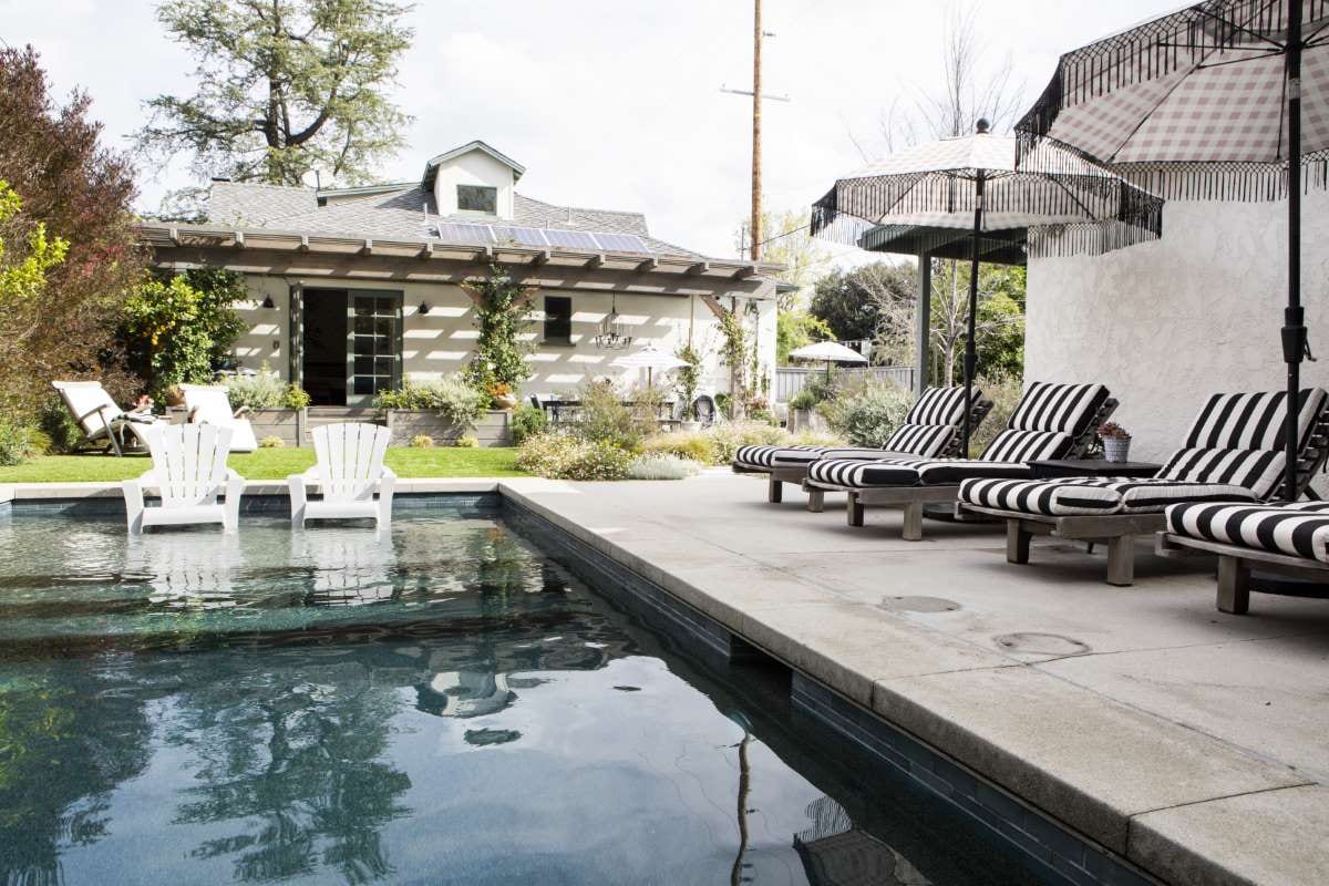 Wooden lounge seats and parasols beside a swimming pool